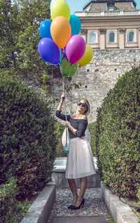 Woman with colorful balloons on walkway against building