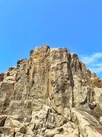 Low angle view of rock formations against clear blue sky