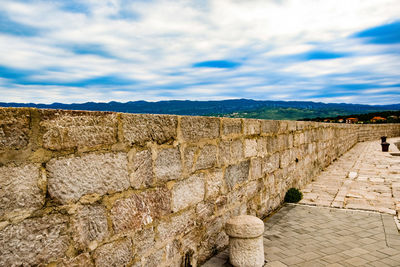 View of stone wall against cloudy sky