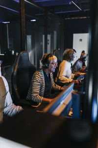 Multiracial elderly male and female friends playing game on computers in gaming center