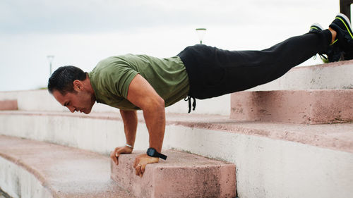 Man doing push up on the step outdoor during rainy day