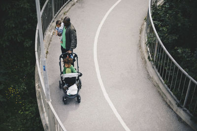 High angle view of father with sons standing on bridge over trees