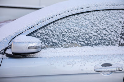 Car covered with a thin layer of fresh white snow. side view.