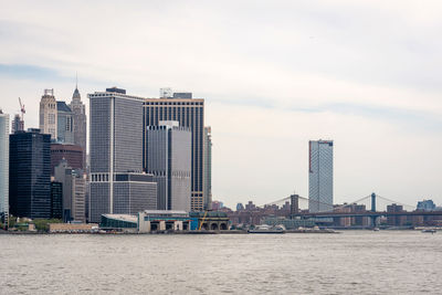 Sea by modern buildings against sky in city