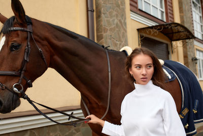 Young woman standing by horse