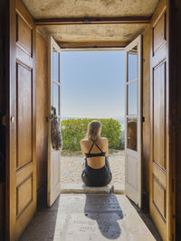 Rear view of woman looking through window