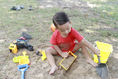 High angle view of boy playing with toys on sand
