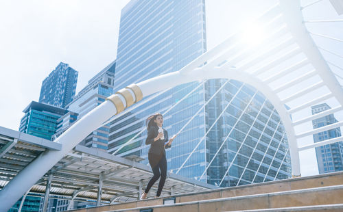 Low angle view of businesswoman moving on steps against buildings in city