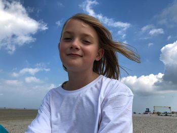 Portrait of smiling girl at beach against sky