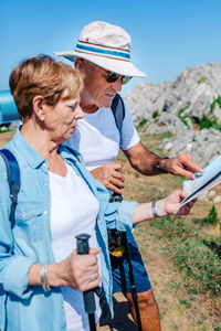 Senior couple trekking looking at map in rocky landscape