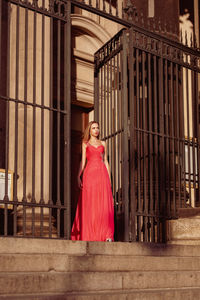 Low angle view of thoughtful woman in pink evening gown standing at doorway