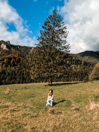 Full length of man sitting on field against sky