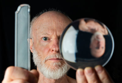 Portrait of man holding camera against black background