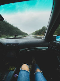 Low section of woman in car against sky