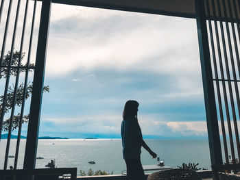 Silhouette woman standing by sea against sky