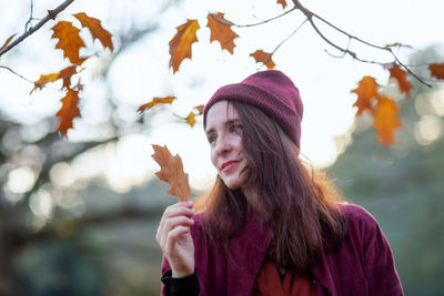 Portrait of young woman in park during autumn
