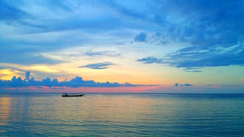 Boats in sea at sunset