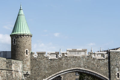 Low angle view of bridge amidst buildings against sky