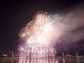 Firework display over river against sky at night