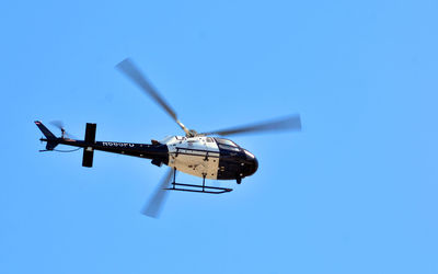 Low angle view of helicopter against clear blue sky