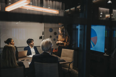 Mature businesswoman planning strategies with male and female colleagues in board room