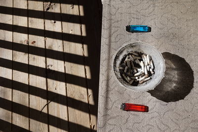 High angle view of cigarette butts in ashtray amidst lighters on table