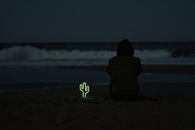 Silhouette man on sea shore at night