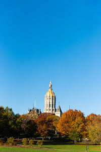 View of trees and buildings against blue sky