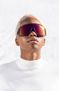 Portrait of young man wearing sunglasses against white background