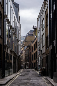 Empty road amidst buildings in city