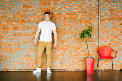 Portrait of muscular man standing by brick wall