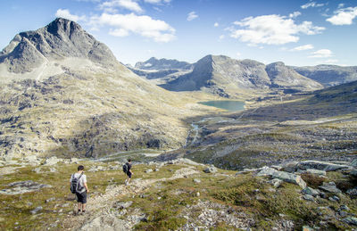 Hikers walking on mountain against sky