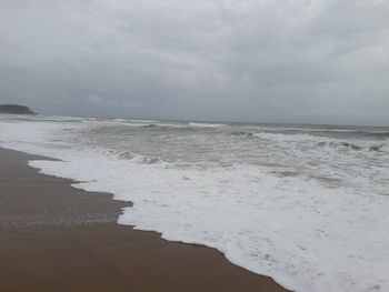 Scenic view of beach against cloudy sky
