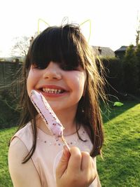 Portrait of smiling girl holding ice cream on field