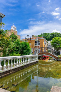 Bridge over canal by building against sky