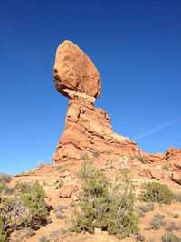 Low angle view of rocky mountains against blue sky