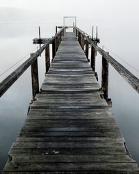 Footbridge over lake during foggy weather