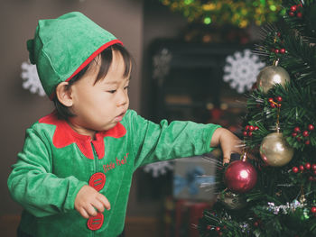 Cute baby girl by christmas tree at home