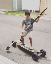 Full length of boy skateboarding on street