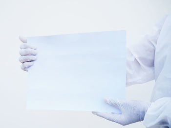 Close-up of hand holding paper over white background