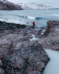 People on rocks at shore during winter