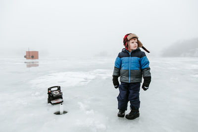 Cute boy standing on frozen field