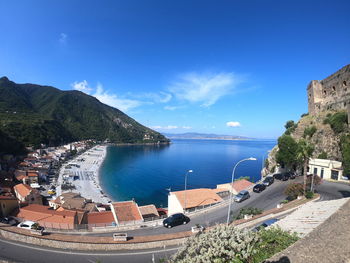 High angle view of buildings by sea against blue sky