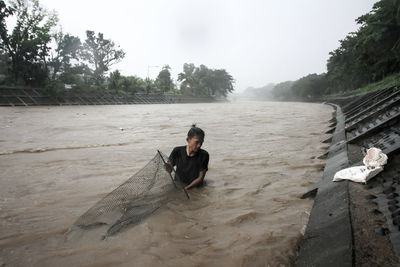 Portrait of youth looking for freshwater fish in the river