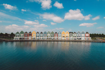 Buildings by river against sky