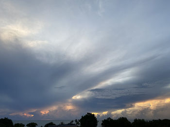 Low angle view of sunlight streaming through clouds