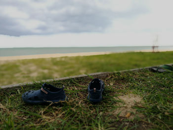 Surface level of shoes on grass by sea