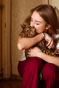 Young woman with cat sitting at home