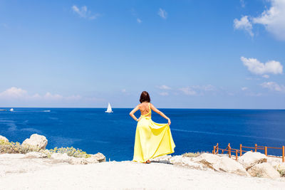 Rear view of woman on beach against sky