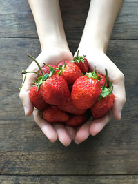 Close-up of human hands holding strawberries on table